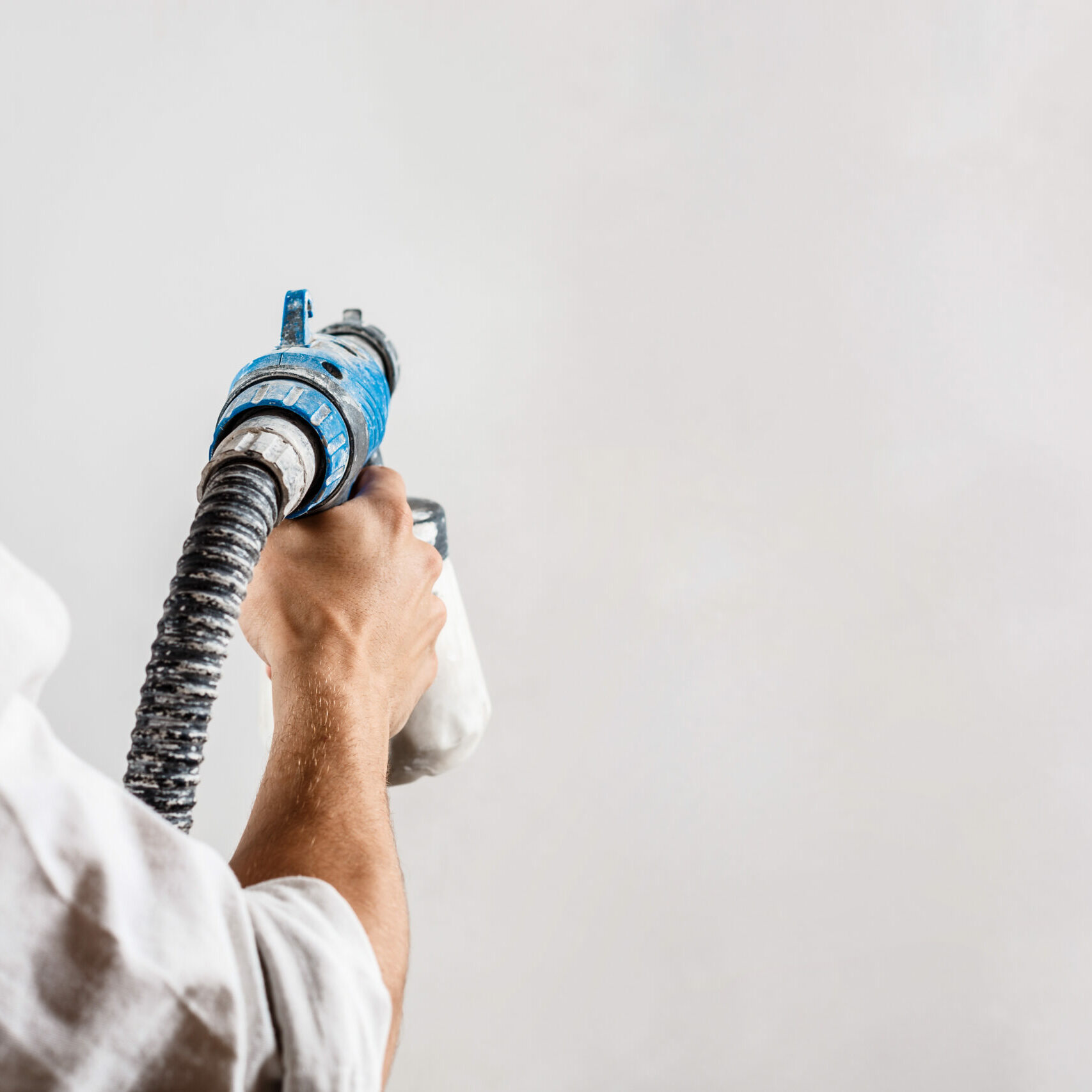 Worker painting wall with spray gun in white color. Worker painting wall with spray gun in white color. Copy space.